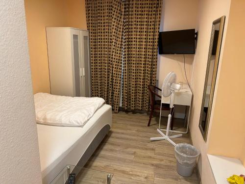 a small room with a bed and a desk with a fan at Relax Hotel-Ludwigshafen in Ludwigshafen am Rhein
