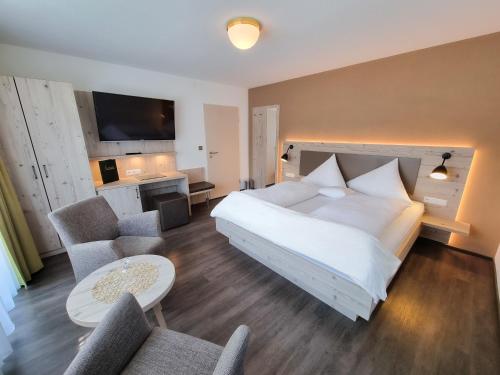 um quarto com uma grande cama branca e 2 cadeiras em Hotel Landhaus Waldesruh em Freudenstadt