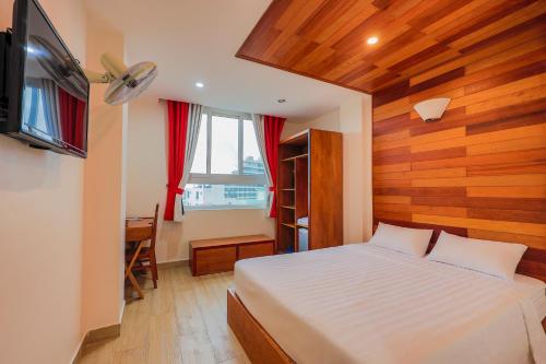 a bedroom with a bed and a desk and a television at Light House Phú Quốc in Phú Quốc