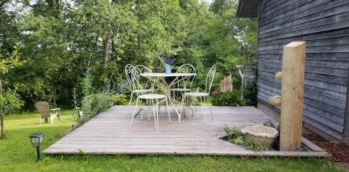 a wooden deck with chairs and a table on it at Gîte de la Tuillère, maison contemporaine en bois avec vue et piscine in Saint-Aulaire