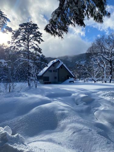 a snow covered field with a barn in the background at FLYING HOUSE in Chikuni