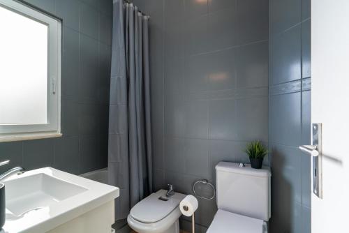 La salle de bains est pourvue de toilettes blanches et d'un lavabo. dans l'établissement Covelo Park Apartment, à Porto