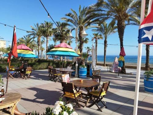 un patio con tavoli, sedie, palme e l'oceano di A&C Algarrobo costa - Malaga a Algarrobo-Costa