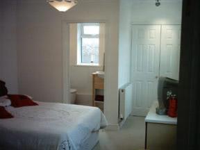 a white bedroom with a bed and a window at Waratah Lodge in South Hayling