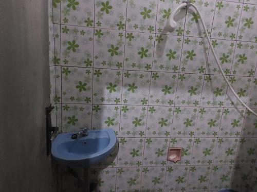 ein Badezimmer mit einem Waschbecken und Blumen an der Wand in der Unterkunft Mountain View Homestay in Tomohon