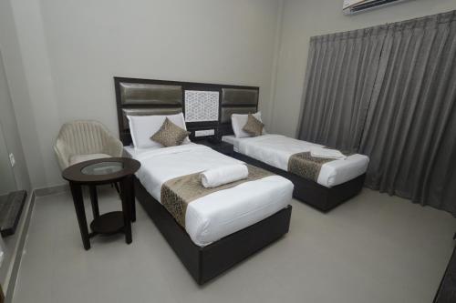 a hotel room with two beds and a chair at Grand Courtyard Business Hotel in Chennai