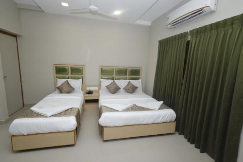 two beds in a room with green curtains at Grand Courtyard Business Hotel in Chennai