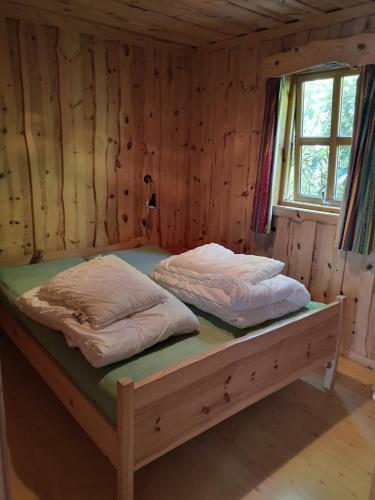 Cama en habitación de madera con 2 almohadas en Fanafjorden Cabins en Bergen