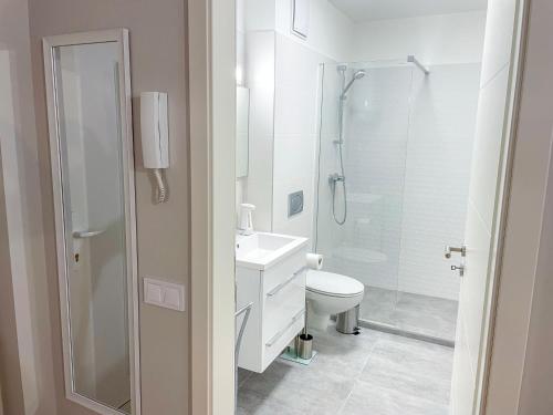 a white bathroom with a shower and a toilet at Aqua Apartman in Zalakaros