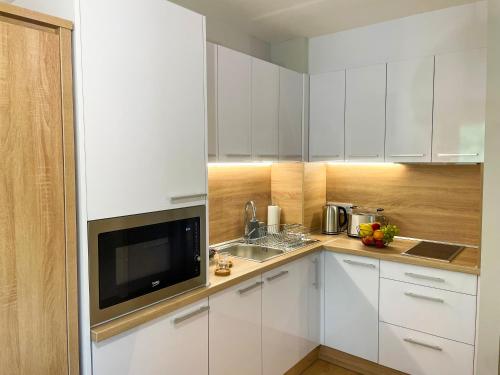 a kitchen with white cabinets and a sink and a microwave at Aqua Apartman in Zalakaros
