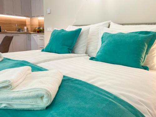 two large white beds with blue pillows in a room at Aqua Apartman in Zalakaros