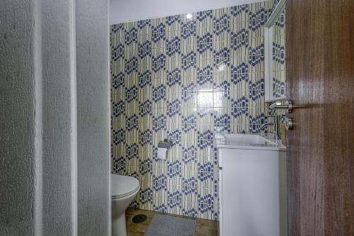 a bathroom with a toilet and blue and white wallpaper at Travel & Live Fernão Magalhães in Porto
