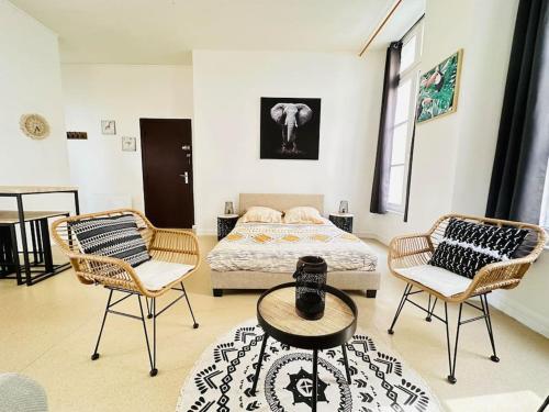 a bedroom with a bed and two chairs and a table at Appartement confortable in Laon