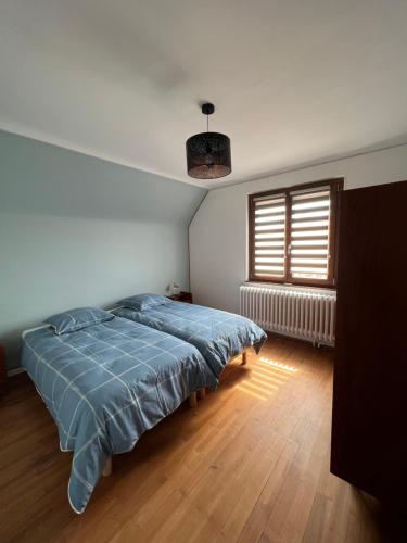 a bedroom with a bed with a blue comforter and a window at Le Cerisier - Route des vins - Parking et terrasse avec vue sur montagnes et vignoble in Sigolsheim