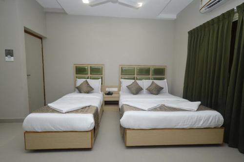 two beds in a room with green curtains at Grand Courtyard Business Hotel in Chennai