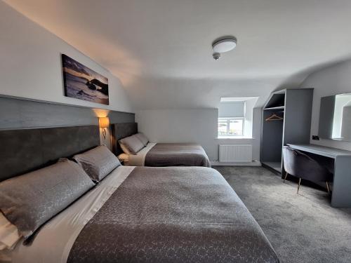 um quarto de hotel com duas camas e uma secretária em Murphy's Guesthouse em Dingle