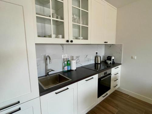 eine Küche mit weißen Schränken und einem Waschbecken in der Unterkunft Lustica Bay - Centrale 1 Bed Apartment in Tivat