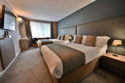a hotel room with two beds and a television at Kensington Court Hotel - Earls Court in London