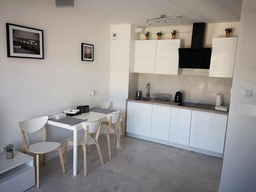 ジブヌベクにあるApartament Baltic Marinaの白いキャビネット、テーブルと椅子付きのキッチンが備わります。