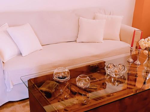 a white couch with glasses on a glass table at Villa 5 Anemoi in Lefkogeia
