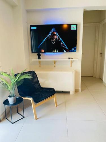 a living room with a chair and a flat screen tv at NEW 2BD Apt with Shared Rooftop Pool in Athens