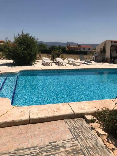 een groot blauw zwembad met stoelen in een tuin bij Villa Vida in Úbeda