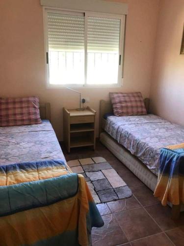 1 Schlafzimmer mit 2 Betten und einem Tisch mit einem Fenster in der Unterkunft Villa Vida in Úbeda