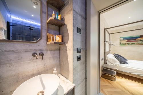 a bathroom with a sink and a mirror and a bed at Sea Garden Apartments & Rooms in Grado