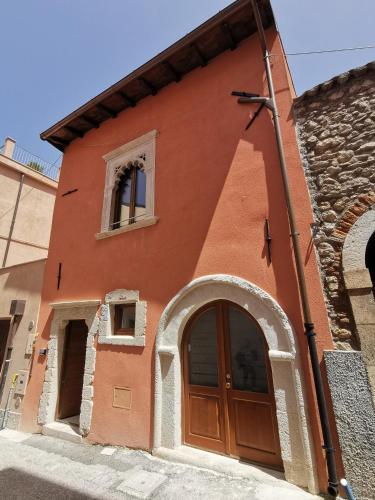 un edificio rojo con puerta y ventana en La Margherita en LʼAquila