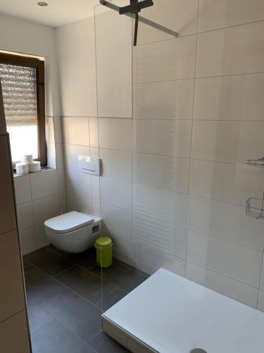 a white bathroom with a toilet and a window at Ferienhaus Lönartz-Thielmann in Ernst