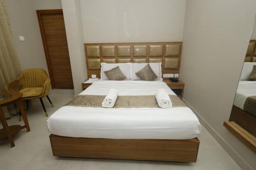 a bedroom with a large bed with white sheets at Grand Courtyard Business Hotel in Chennai