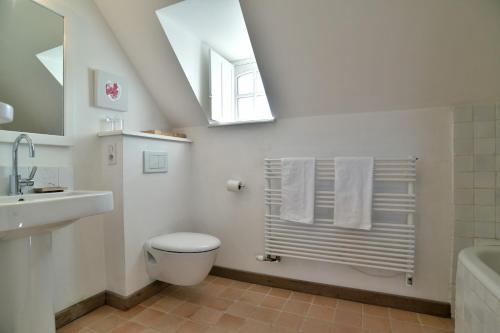 une salle de bain blanche avec des toilettes et un lavabo dans l'établissement Le Verger - Charmante maison avec jardin, à Saint-Lunaire