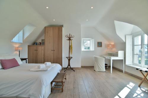 1 dormitorio con cama blanca y escritorio en Le Verger - Charmante maison avec jardin, en Saint-Lunaire