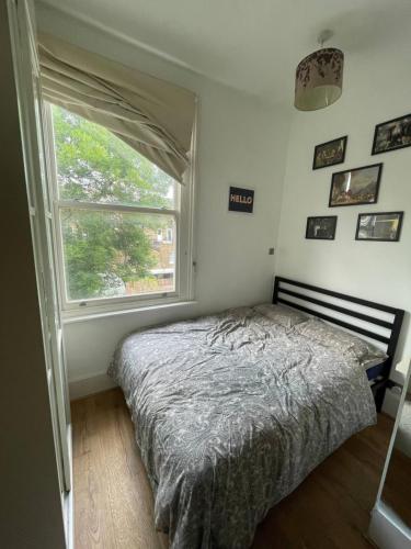 a bedroom with a bed and a large window at Stylish 1BD Flat with Private Terrace - Kilburn in London