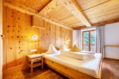 1 dormitorio con 1 cama en una pared de madera en Mitterbruggehof Apt Enzian en Anterselva di Mezzo