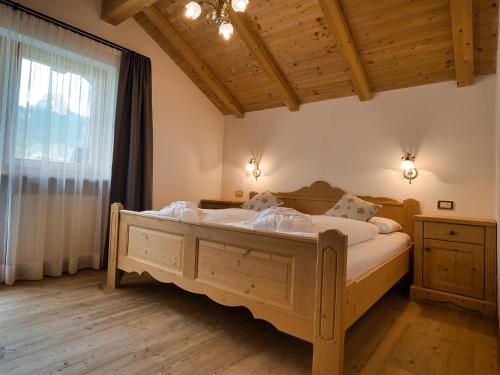 ein Schlafzimmer mit einem Holzbett in einem Zimmer mit einem Fenster in der Unterkunft Aparthotel Monte 44 in Wolkenstein in Gröden