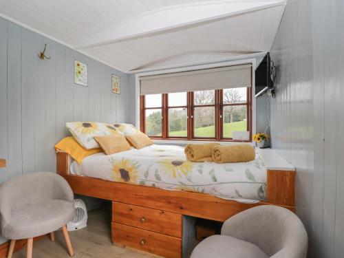 a bedroom with a bed with a window and two chairs at Rabbit Hill Hut in Abergavenny