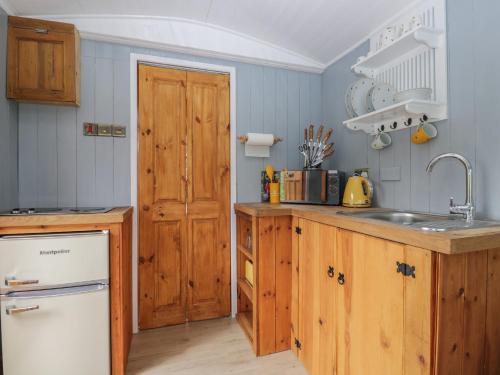 a kitchen with wooden cabinets and a sink at Rabbit Hill Hut in Abergavenny