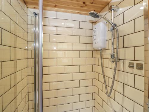 a shower in a bathroom with white tiles at Rabbit Hill Hut in Abergavenny