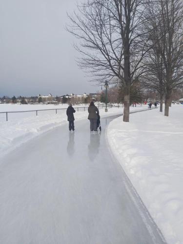 two people walking down a snow covered sidewalk at O'Berge du Village C304 - Bord de l'eau in Magog-Orford