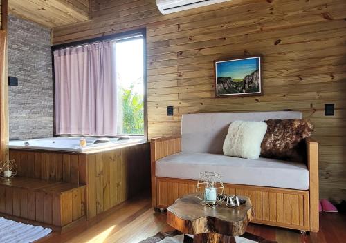 um quarto com uma banheira, uma cama e uma mesa em AriMara Chalés & Ecoturismo em Praia Grande