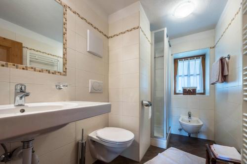 a white bathroom with a sink and a toilet at Mitterbruggehof Apt Alpenrose in Anterselva di Mezzo