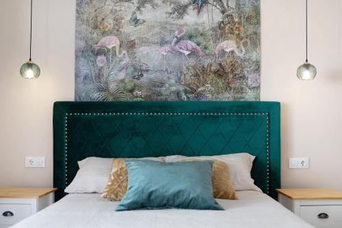 une chambre avec une tête de lit verte et une peinture murale dans l'établissement Villa Alegría, à Chiclana de la Frontera