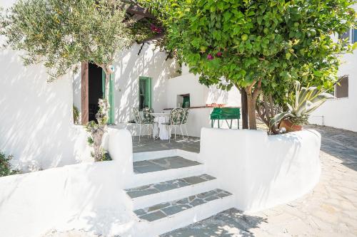 a white house with stairs and a table and trees at Fedra's Traditional House in Psinthos