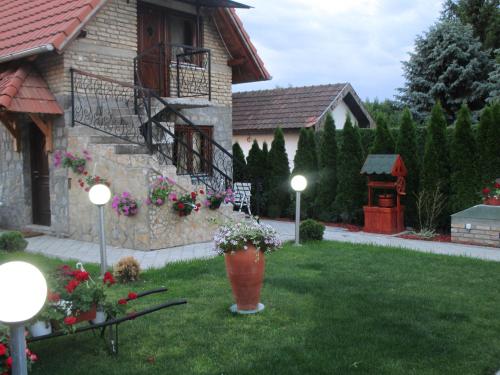 a yard with a house with flowers and lights at Vila Boska Palic in Palić
