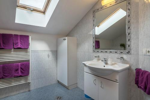 ein Badezimmer mit einem Waschbecken, einem Spiegel und lila Handtüchern in der Unterkunft Woehrmannhof Apt Birnblüte in Feldthurns