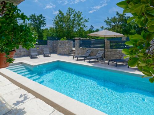 a swimming pool with chairs and an umbrella at Holiday Home Pahari by Rent Istria in Roč