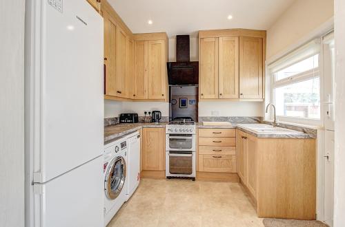 een keuken met witte apparaten en houten kasten bij Seaside king room in cozy house self check-in fast WiFi in New Brighton