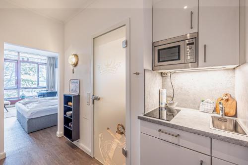 a kitchen with a sink and a microwave at fewo1846 - Marina del Rey - elegantes Studioapartment mit Meerblick und eigenem Strandkorb in Glücksburg