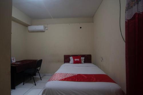 Un dormitorio con una cama con una almohada roja. en OYO 92714 Miracle Kost, en Manado